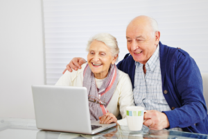 older couple sit happily before a laptop screen