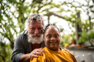 grandfather smiles next to his grandchild with special needs